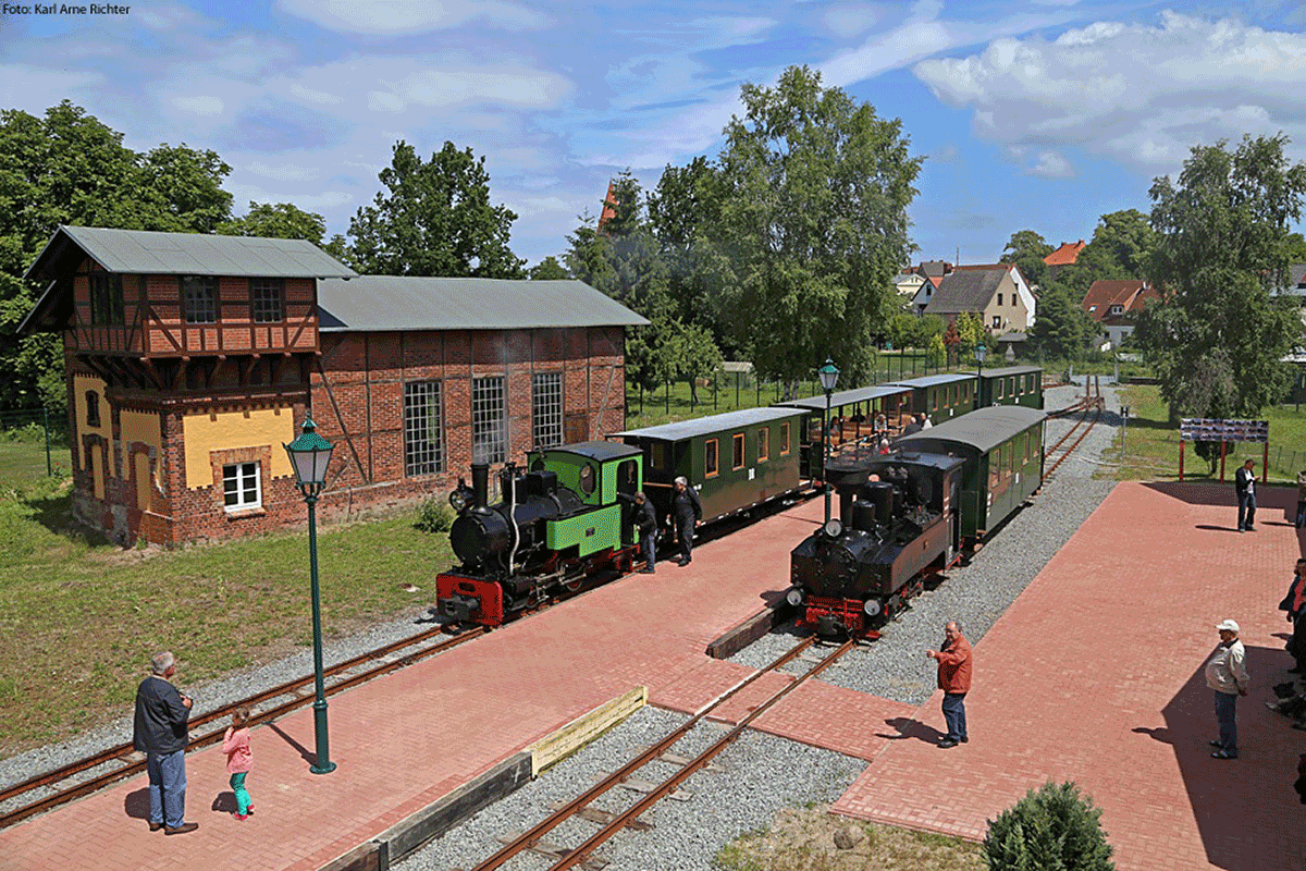 Blick auf Bahnhof mit zwei historischen Kleinbahn-Zügen